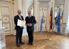 Regierungspräsident Walter Jonas überreicht Kreisbrandinspektor Marco Greil (Landkreis Cham) das Steckkreuz für besondere Verdienste um das Feuerwehrwesen.