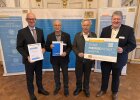 Regierungspräsident Walter Jonas mit Josef Langgärtner, Anton Hösl und Bernhard Schmidt von der Bürgerenergiegenossenschaft Parkstein eG. Zwei halten eine Urkunde und ein Unterstützer-Schild.