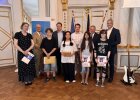 Vier Jugendliche der Realschule am Judenstein stehen mit Urkunden und Preisumschlägen gemeinsam mit Lehrkräften und Ehrengästen im Großen Sitzungssaal.