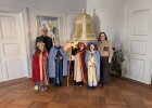 Regierungspräsident Walter Jonas und Regierungsvizepräsidentin Christiane Zürn stehen gemeinsam mit vier als Sternsinger verkleideten Kindern in einem historischen Raum der Regierung der Oberpfalz. Die Kinder tragen bunte Gewänder, Kronen und einen Stern.